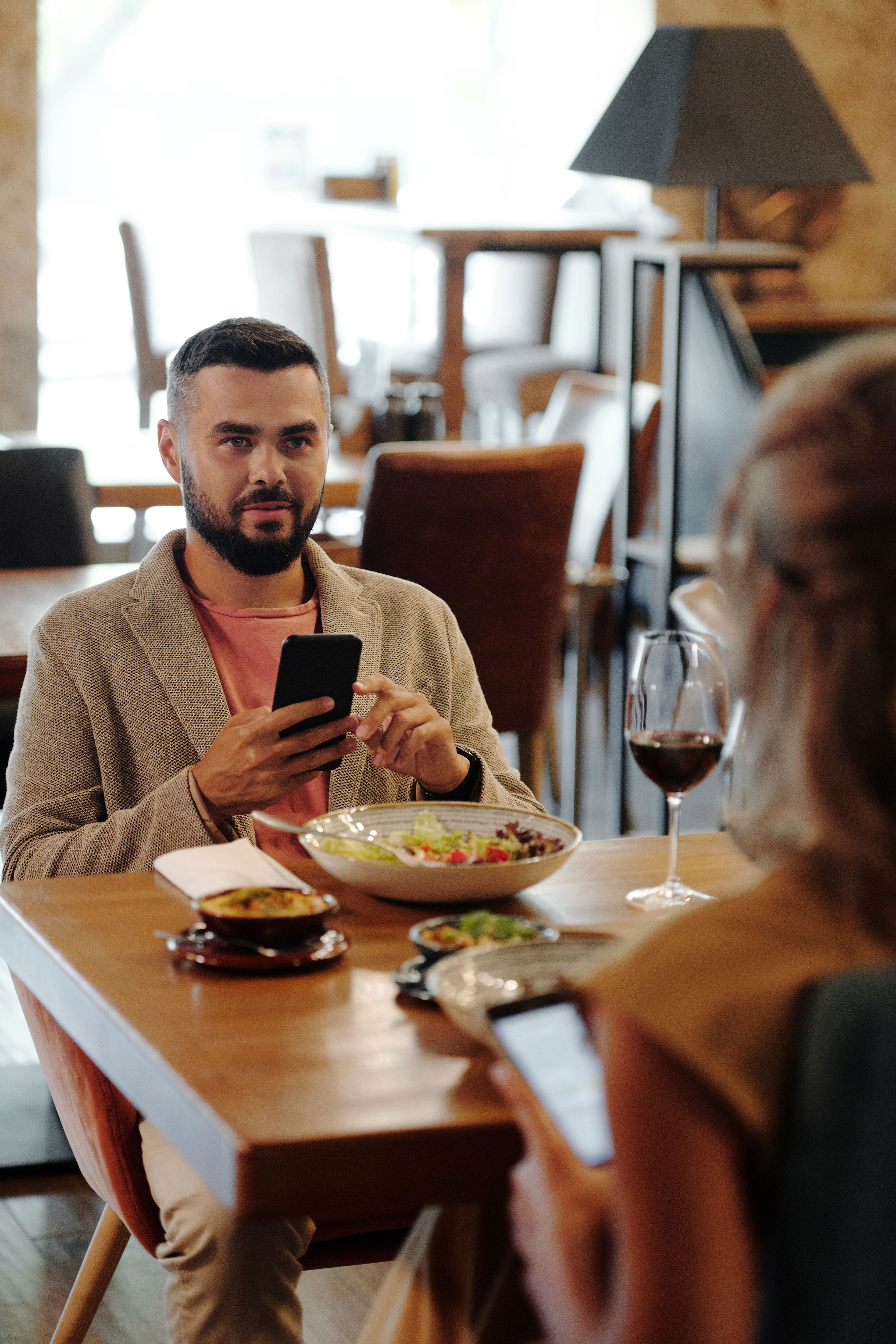 Man and woman sitting at a restaurant table both using smartphones during a date
