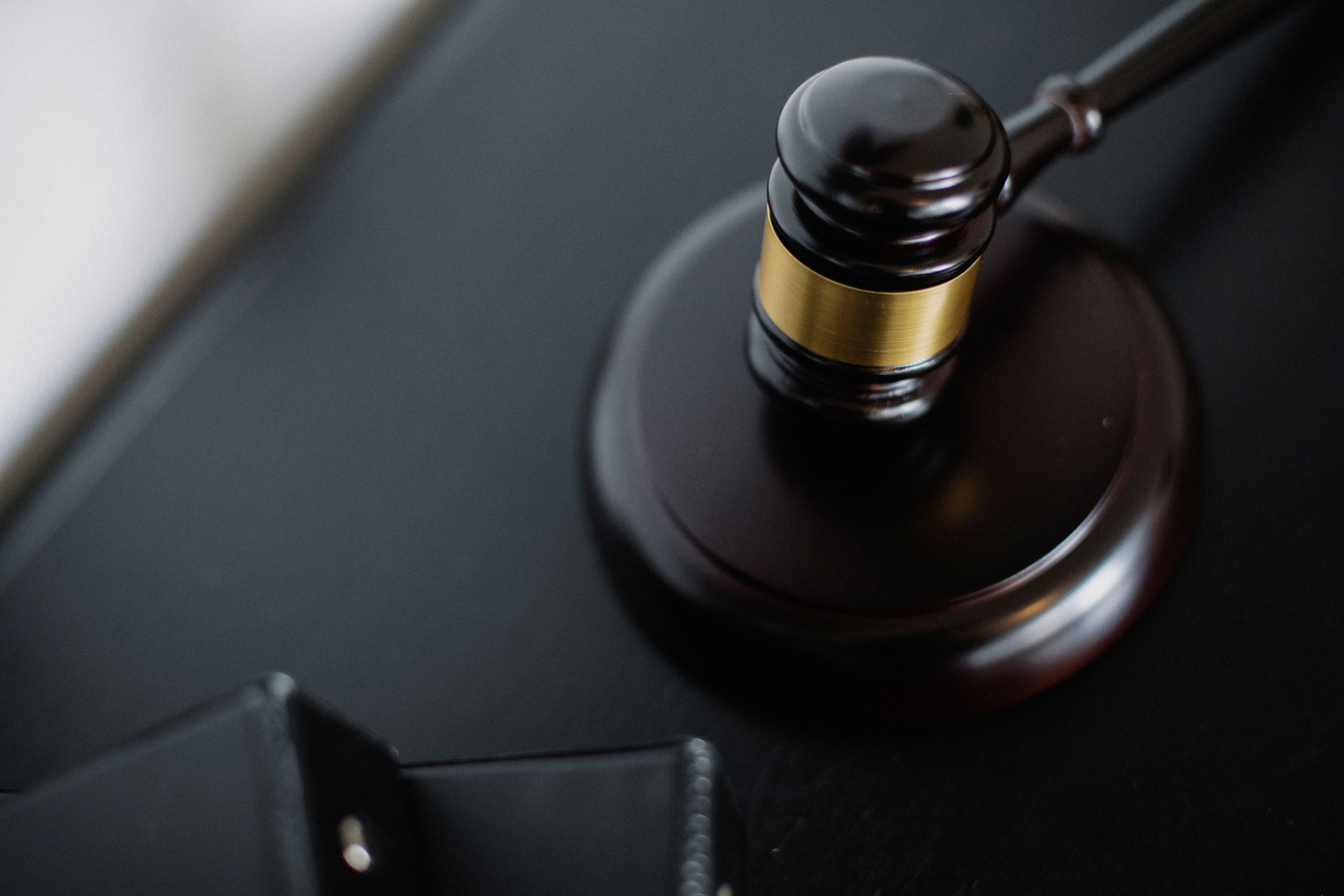 Wooden courtroom gavel beside legal folders on a table