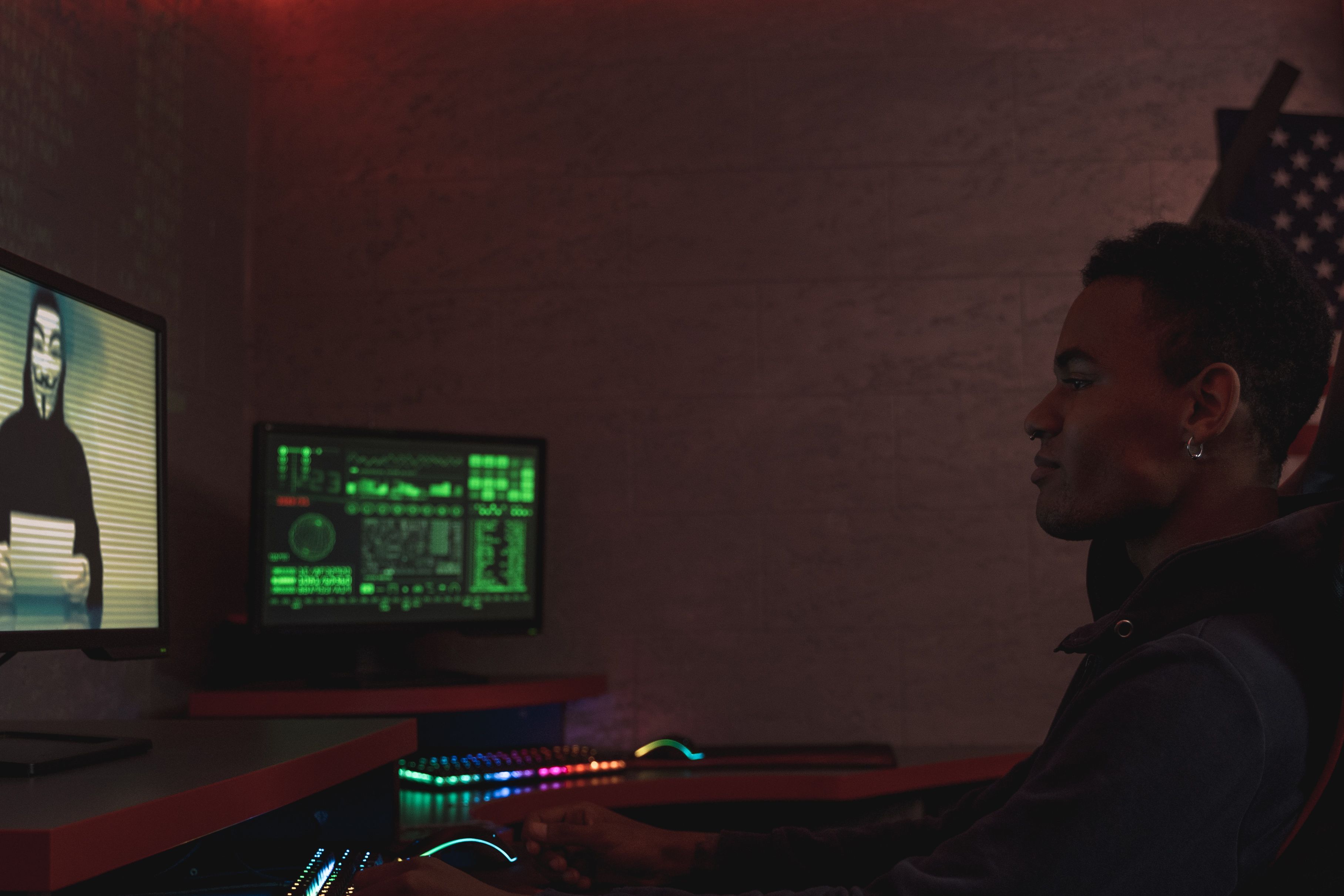 Cybersecurity professional monitoring data systems in a dark room, symbolizing digital threats to elections