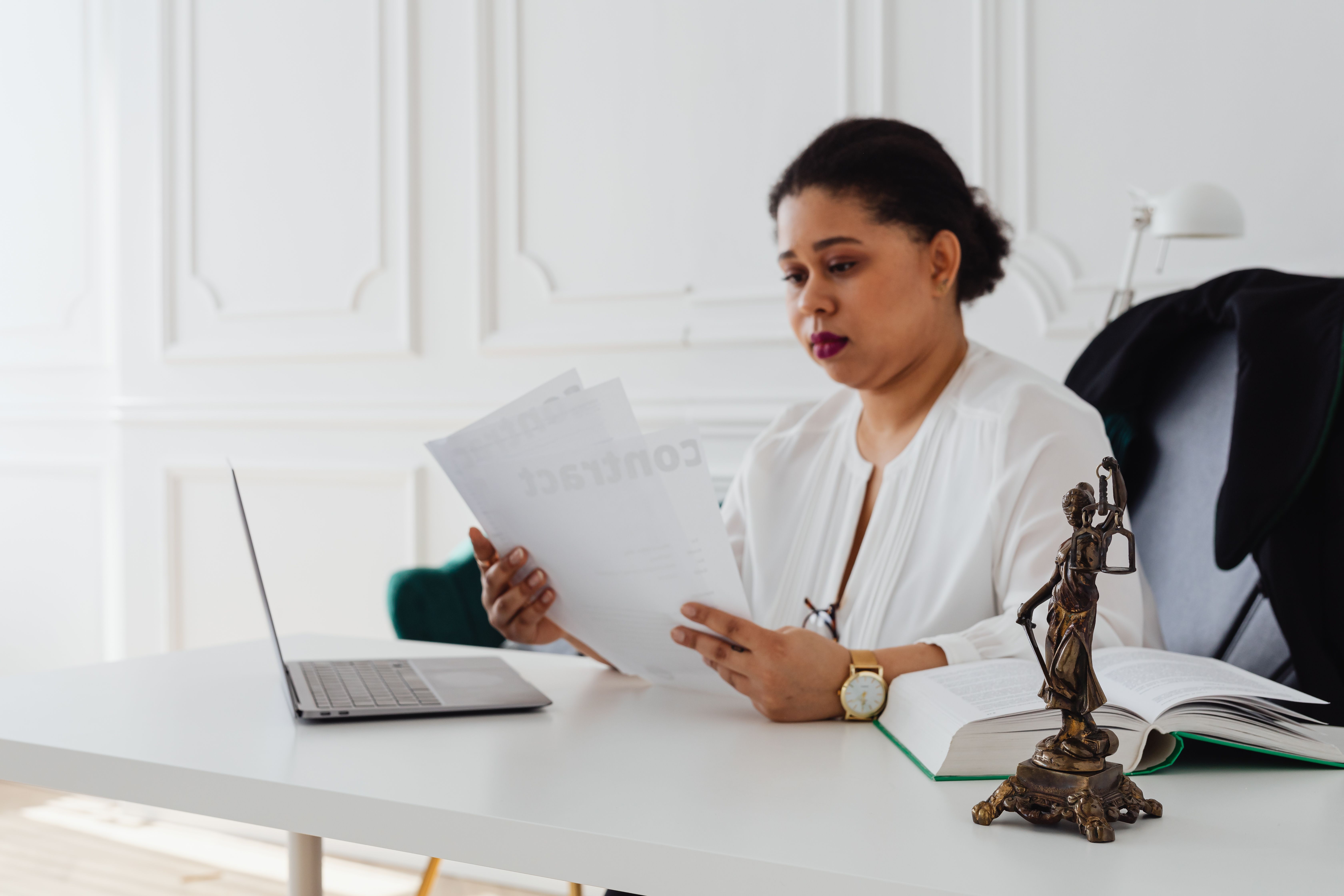 Black woman lawyer reading legal papers at her desk in a modern office