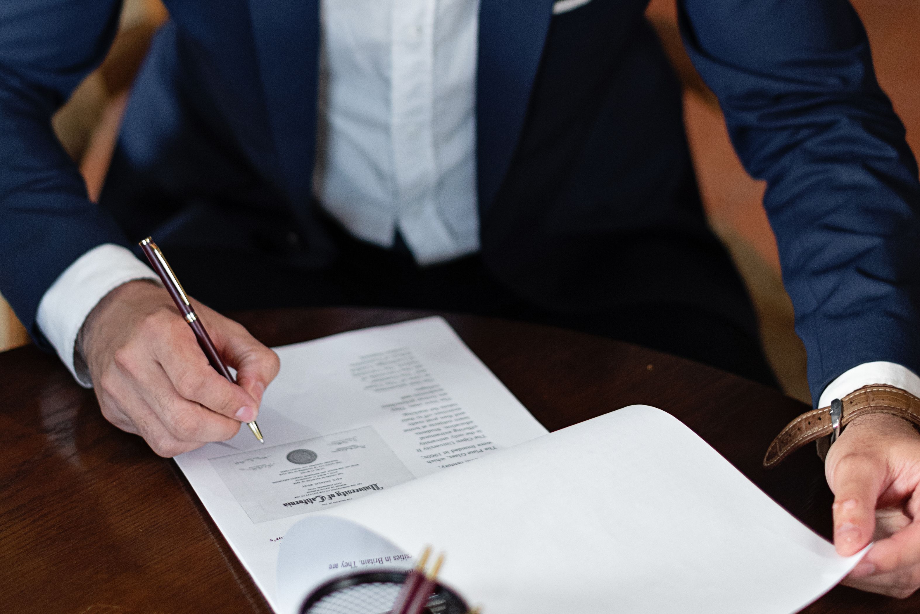 Professional signing legal documents at an office desk