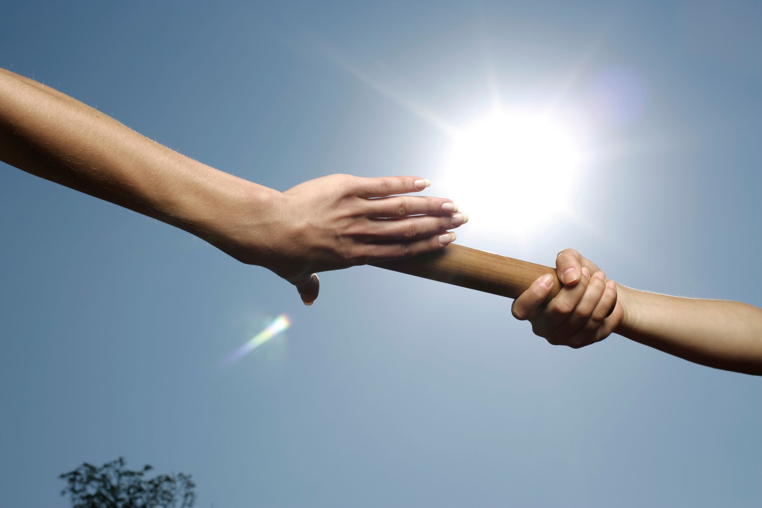 Two hands passing a baton, symbolizing leadership succession and continuity