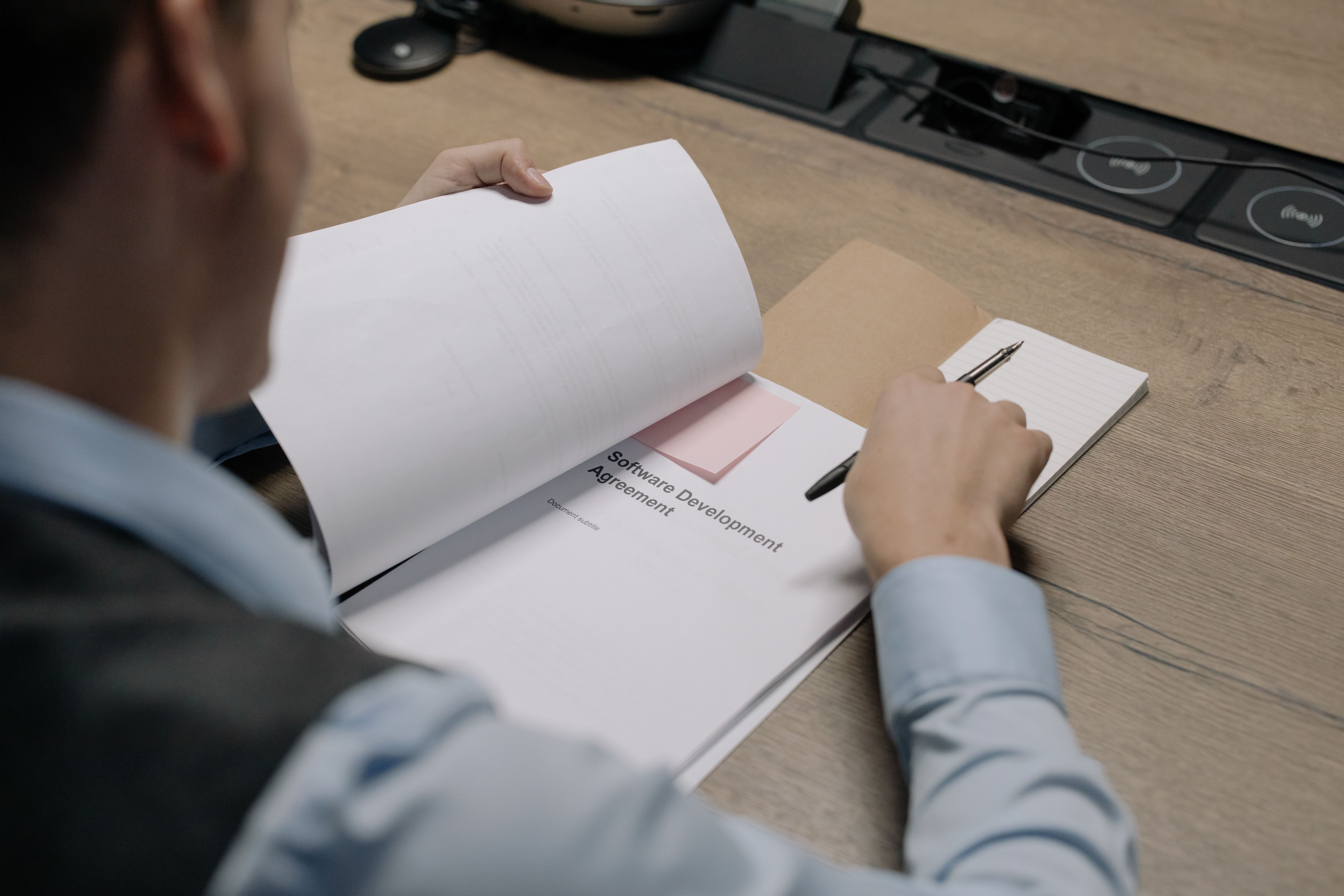 Business professional at a desk examining a software development agreement document
