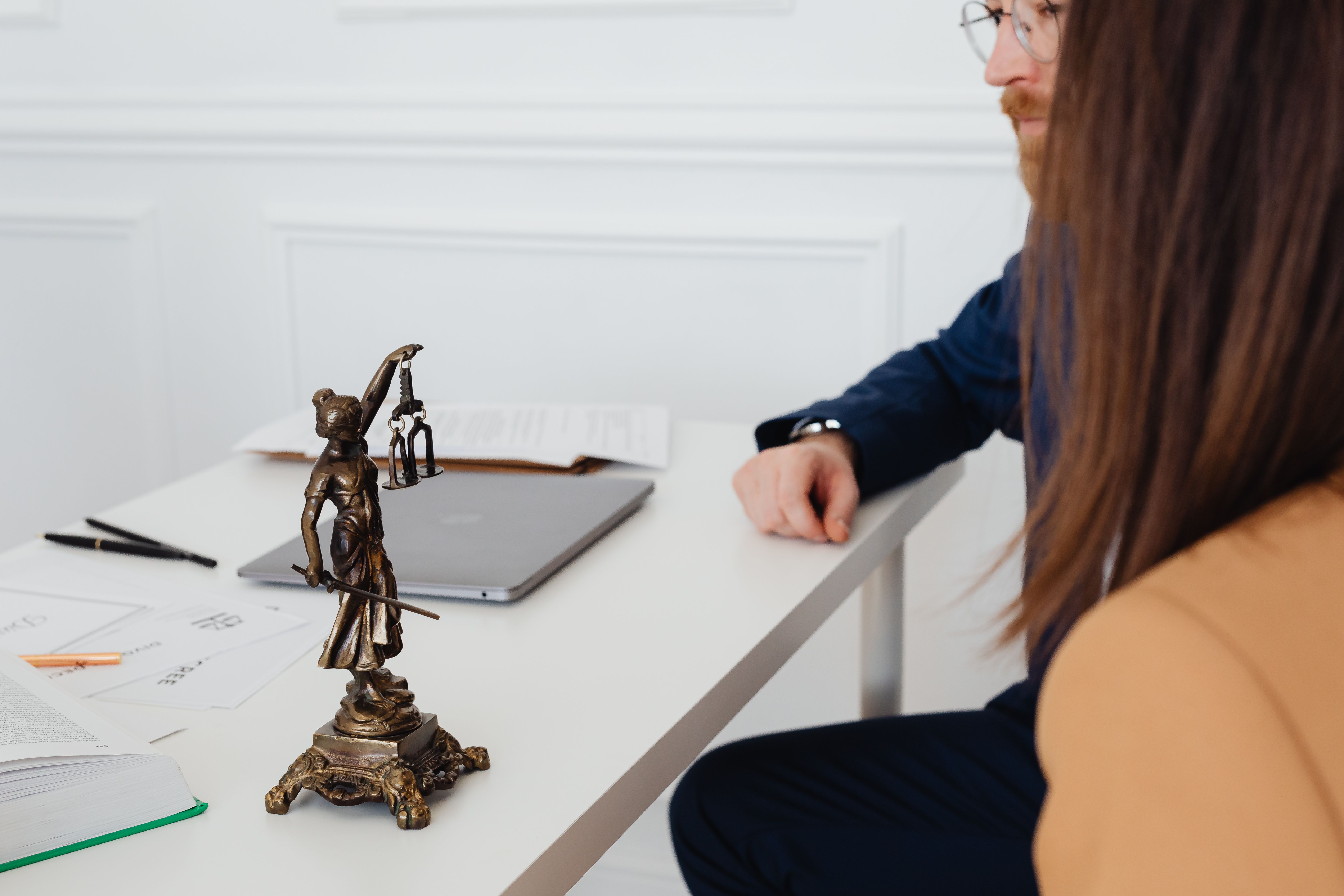 Lawyers reviewing legal documents beside a Lady Justice statue in a professional office