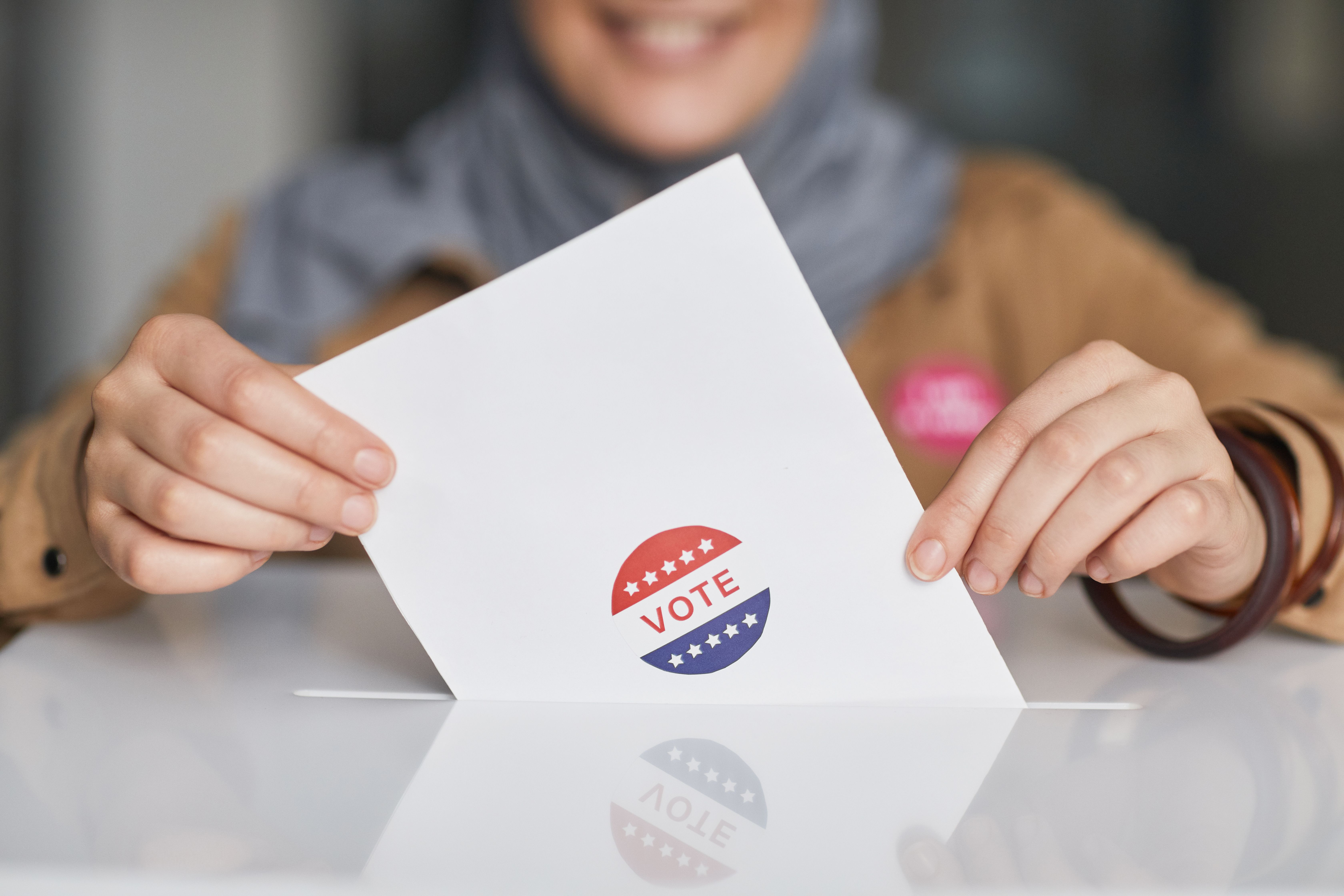 Close-up of hands holding a vote ballot, representing election participation in Southeast Asia