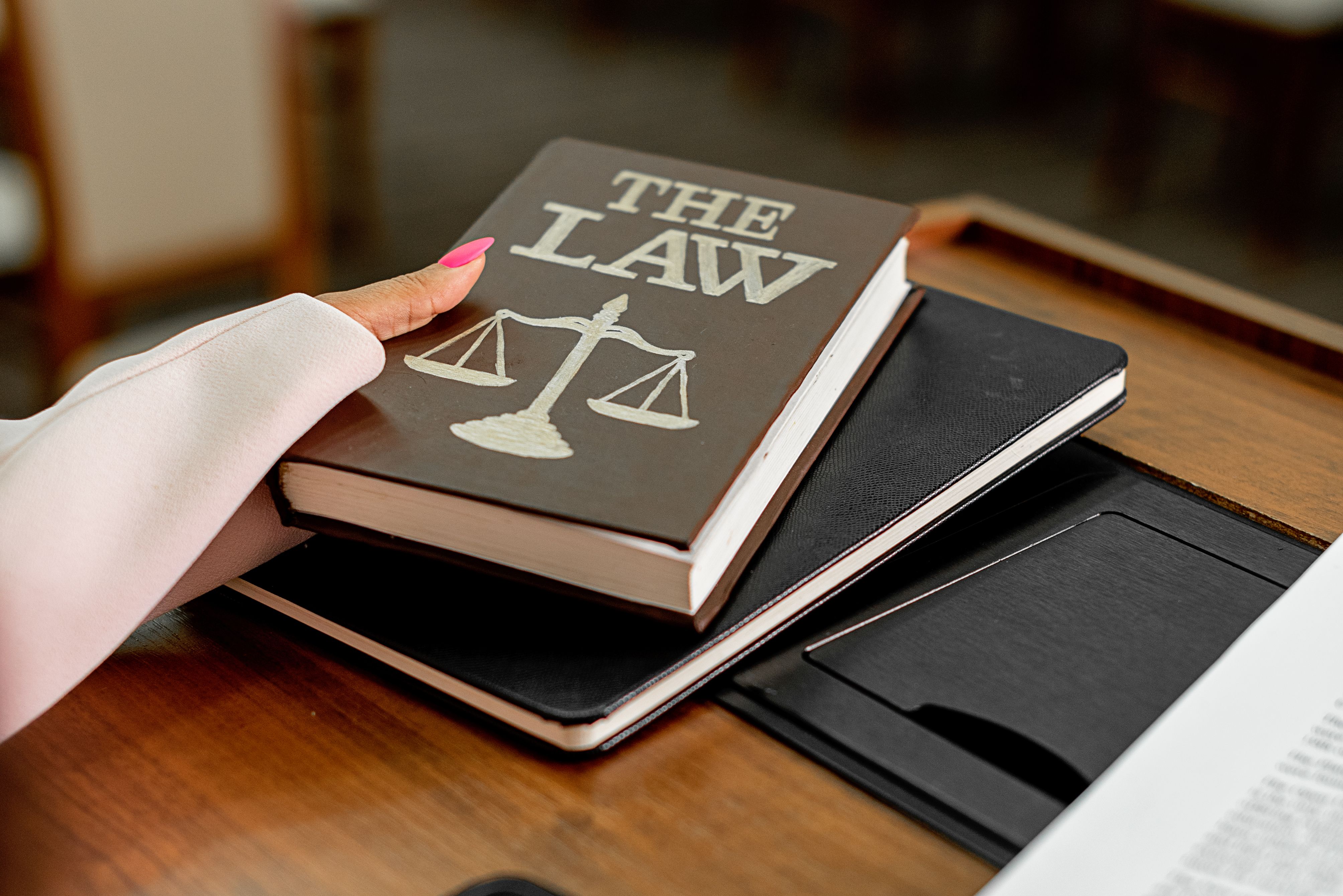 Close-up of a law book titled The Law on a wooden desk with scales of justice